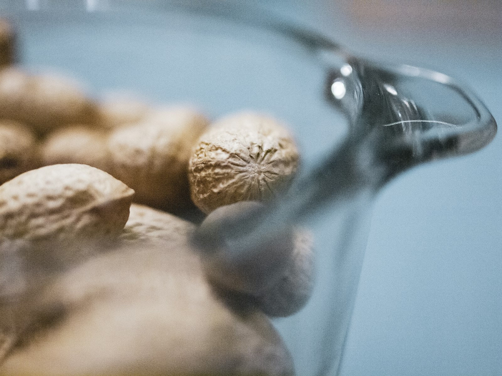 Olive oil being poured into a small glass bowl beside walnuts