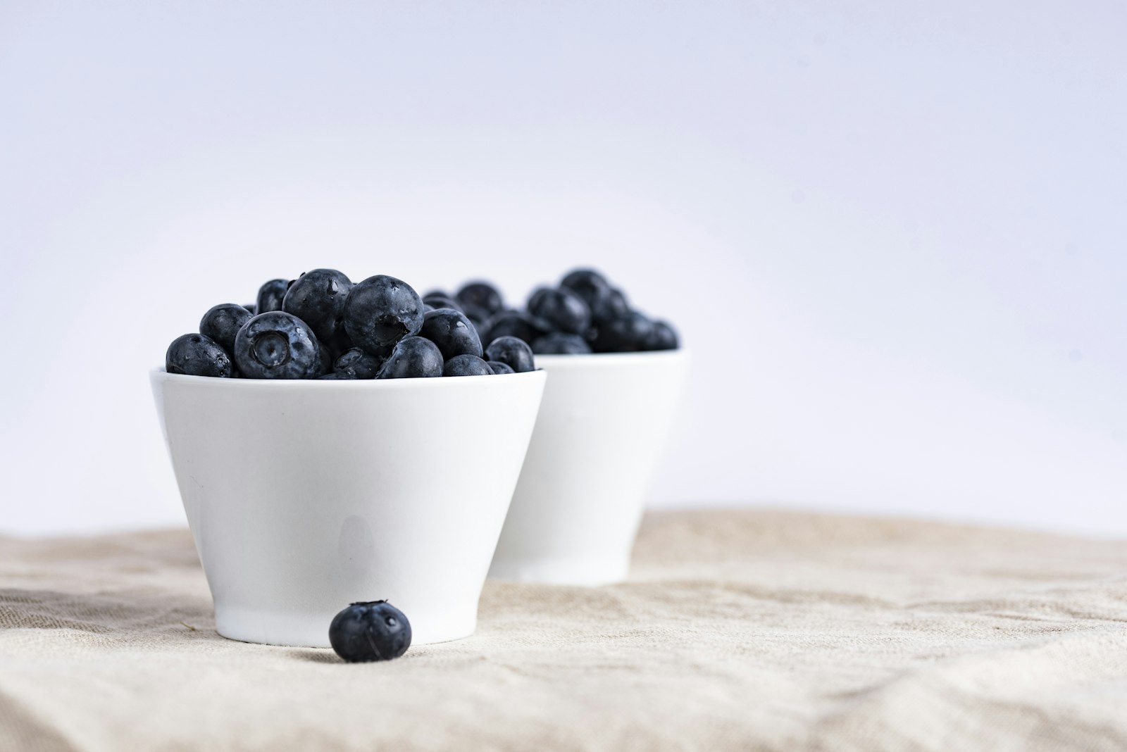 Two similar yoghurt pots side by side on a pale surface